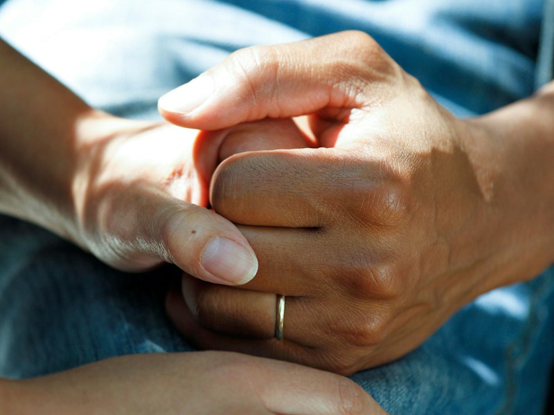 A caregiver gently holding the hands of an elderly person
