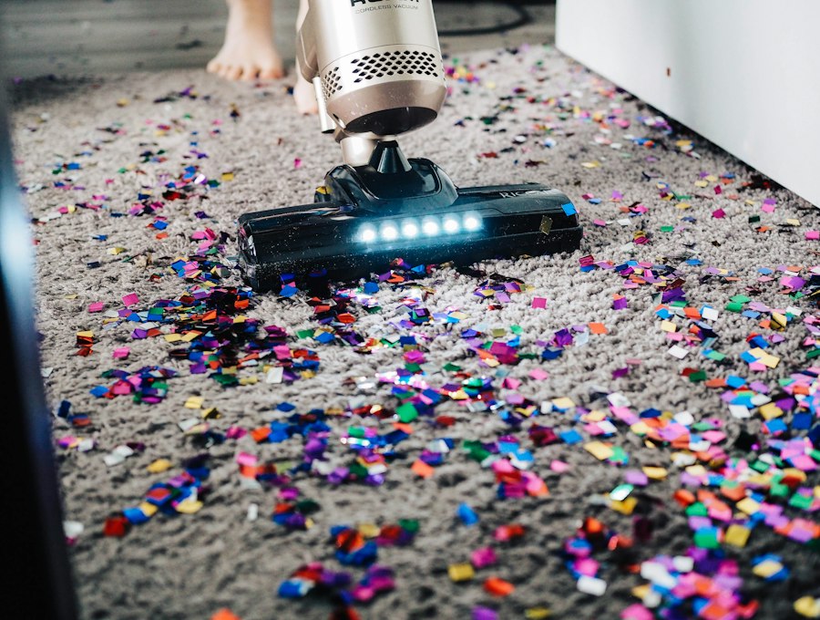 A vacuum cleaner being used on a carpet covered in colourful party confetti