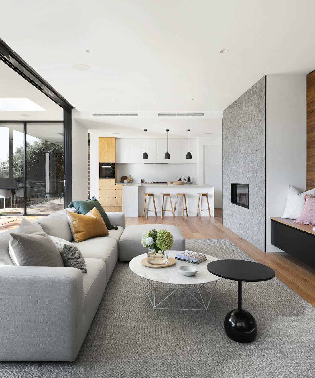 A bright, freshly cleaned living room with a sofa, warm wood floors and soft natural light