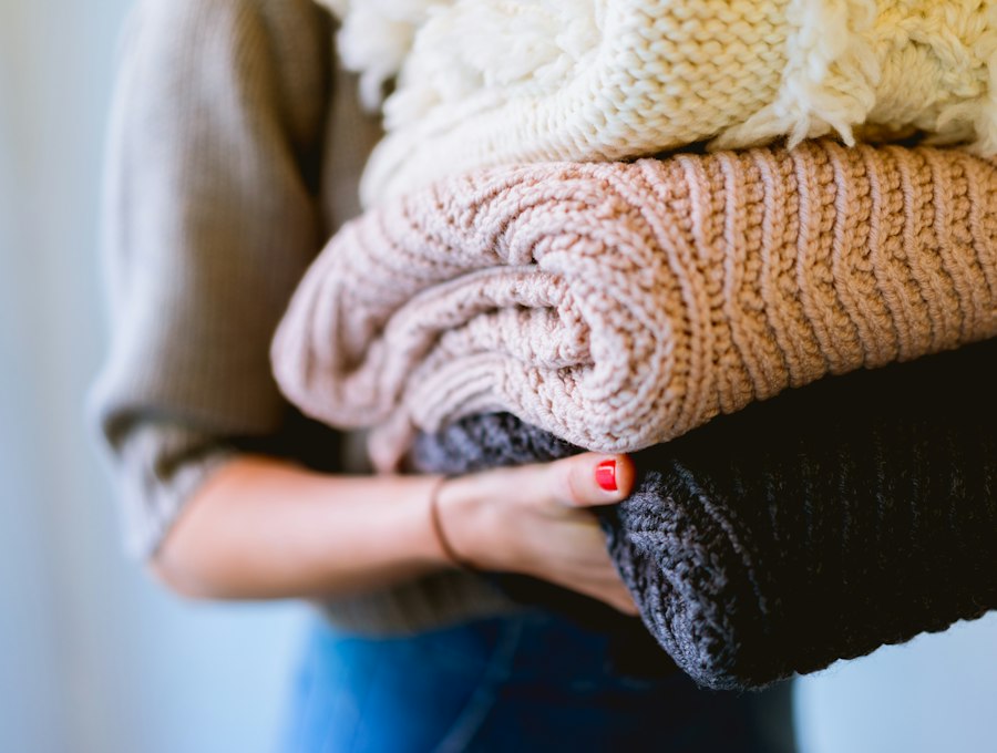 A neatly folded stack of woollen clothes held in someone's arms